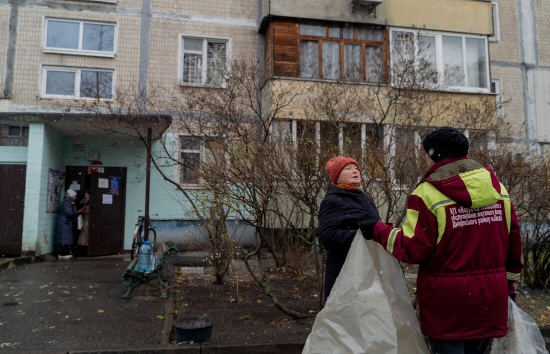 Pessoas se preparam para cobrir janelas de um prédio residencial após um ataque de drone russo em Kiev