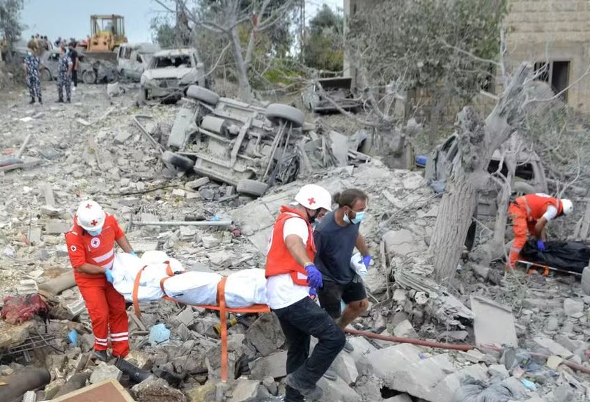 Paramédicos da Cruz Vermelha Libanesa transportam um corpo desenterrado dos escombros no local de um ataque aéreo israelense 