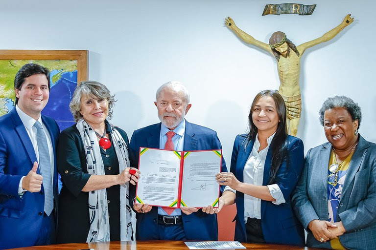 O ministro André Fufuca (Esporte), a deputada Erika Kokay (autora da lei), o presidente Lula, a senadora Eliziane Gama e a ministra Macaé Evaristo (Direitos Humanos e Cidadania)