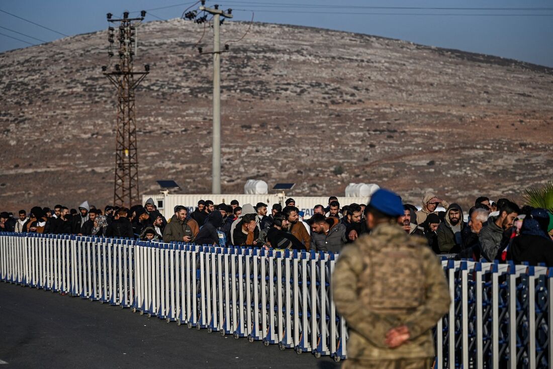 Sírios que vivem na Turquia esperam numa fila no portão transfronteiriço de Cilvegozu antes de entrar na Síria