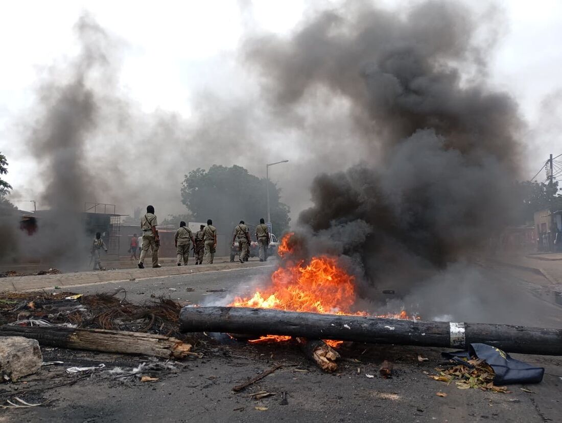 Pedestres passam por uma barricada em chamas em Maputo em 24 de dezembro de 2024.