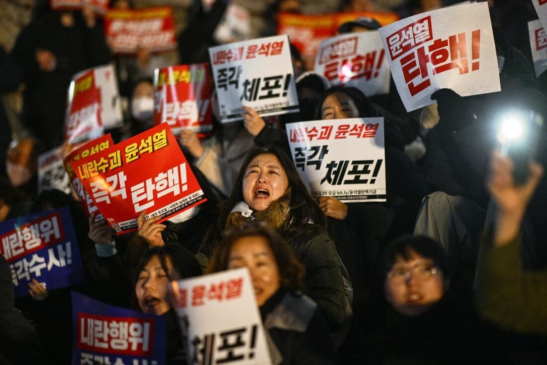 Pessoas participam de um protesto pedindo a renúncia do presidente da Coreia do Sul, Yoon Suk Yeol, na Assembleia Nacional em Seul.