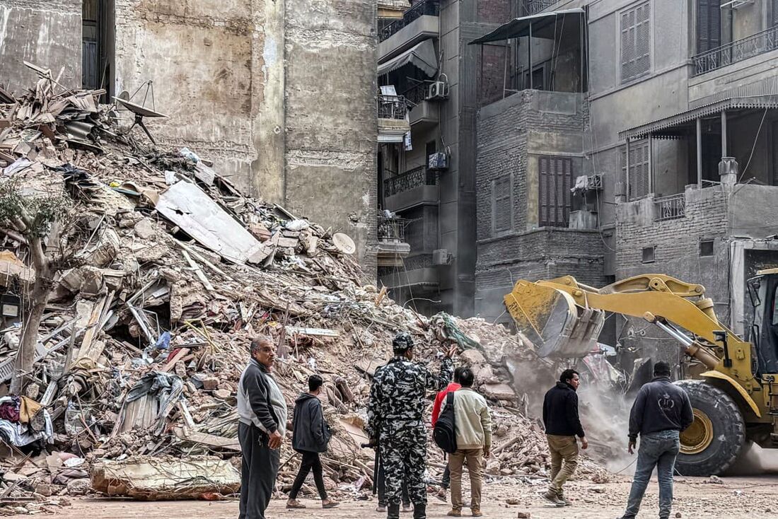 Uma escavadeira limpa escombros do local de um prédio que desabou no distrito de Waili, no centro do Cairo, em 10 de dezembro de 2024. 