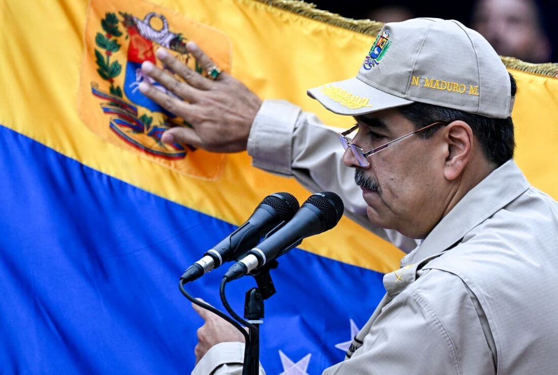 O presidente da Venezuela, Nicolás Maduro, toca uma bandeira venezuelana enquanto discursa durante um evento