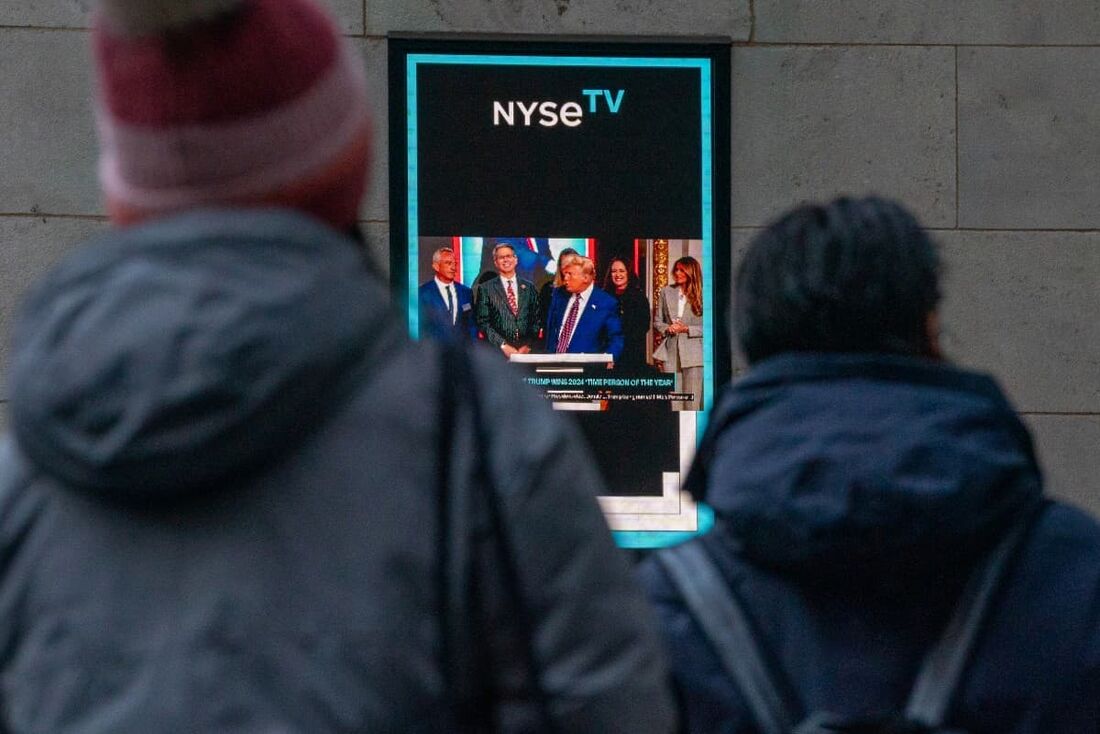 Pessoas na rua assistem enquanto o presidente eleito dos EUA, Donald Trump, é exibido em uma tela (1)