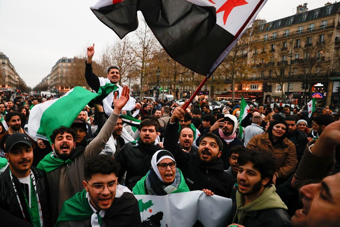 Apoiadores balançando a bandeira da indepedência da Siria na França, em comemoração à queda do presidente Bashar al-Assad