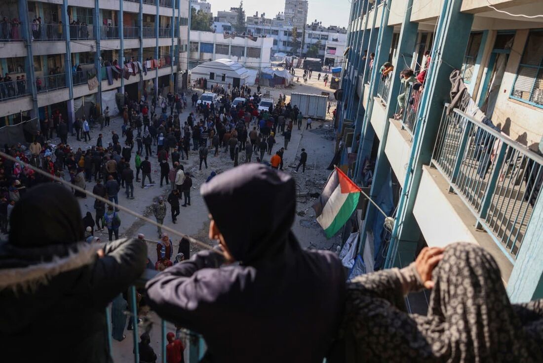 Pessoas inspecionam os danos após os ataques israelenses à escola Ahmad Abdulaziz administrada pela UNRWA, que atualmente abriga famílias deslocadas em Khan Yunis, no sul da Faixa de Gaza