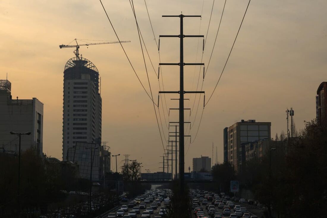 O tráfego flui em uma estrada principal passando por torres de transmissão de eletricidade em Teerã em 16 de dezembro de 2024.