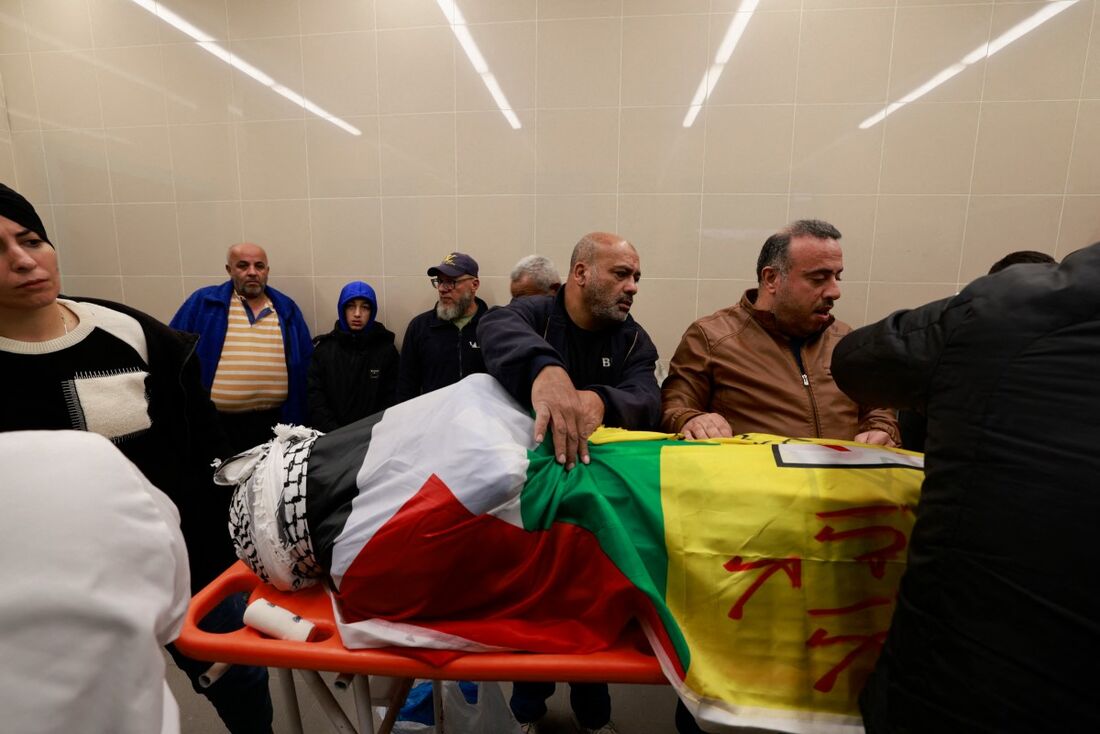 Os palestinos preparam o corpo de um homem, morto junto com outros três em um ataque israelense a um veículo no dia anterior, antes de seu funeral