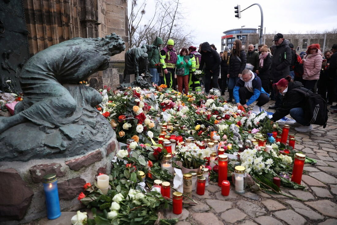 Pessoas depositam flores e velas no local de um ataque de atropelamento em um mercado de Natal em Magdeburg, no leste da Alemanha.