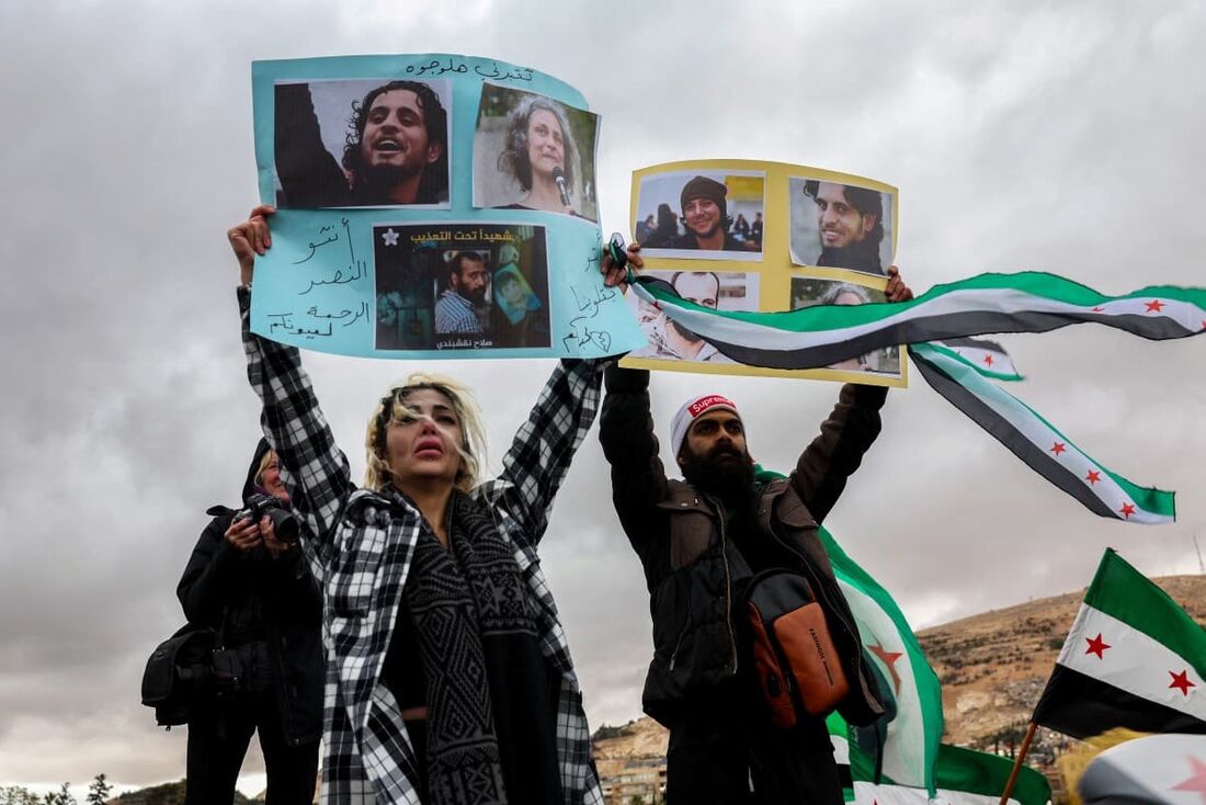 Pessoas seguram fotos de pessoas desaparecidas durante uma manifestação celebrando a queda do presidente sírio Bashar al-Assad na Praça Ummayad, na capital Damasco, em 27 de dezembro de 2024.