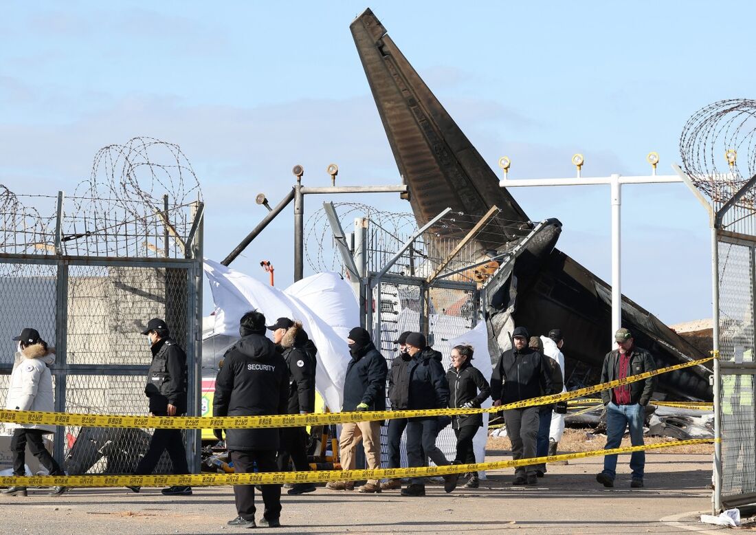 Investigadores da Coreia do Sul e dos EUA, incluindo autoridades do National Transportation Safety Board (NTSB) dos EUA e da fabricante de aeronaves Boeing, inspecionam a cena onde uma aeronave Boeing 737-800 da Jeju Air caiu e pegou fogo