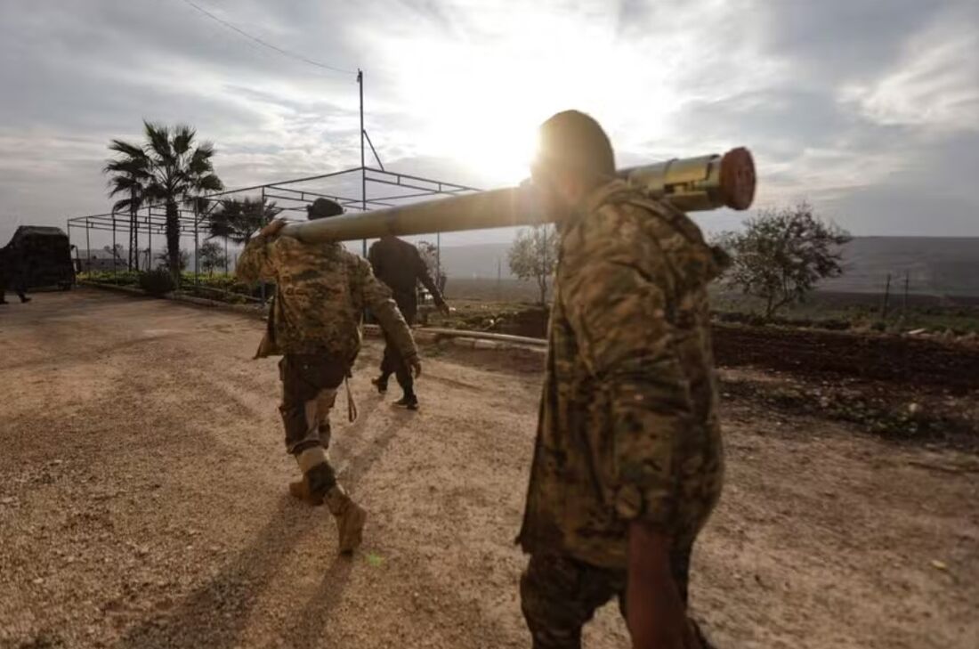 Combatentes carregam foguete na periferia da cidade de Hama, na Síria 