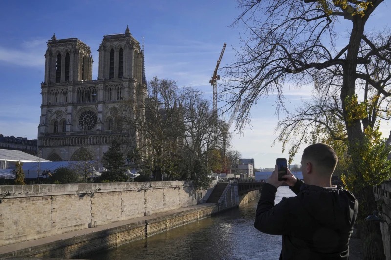 Homem tira uma foto da Catedral de Notre Dame renovada