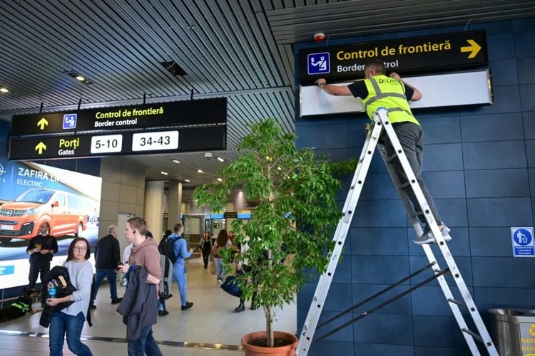 Funcionário troca sinalizações no aeroporto Henri Coanda de Otopeni, na Romênia, em 28 de março de 2024, antes da incoporação parcial do país no espaço Schengen de livre circulação