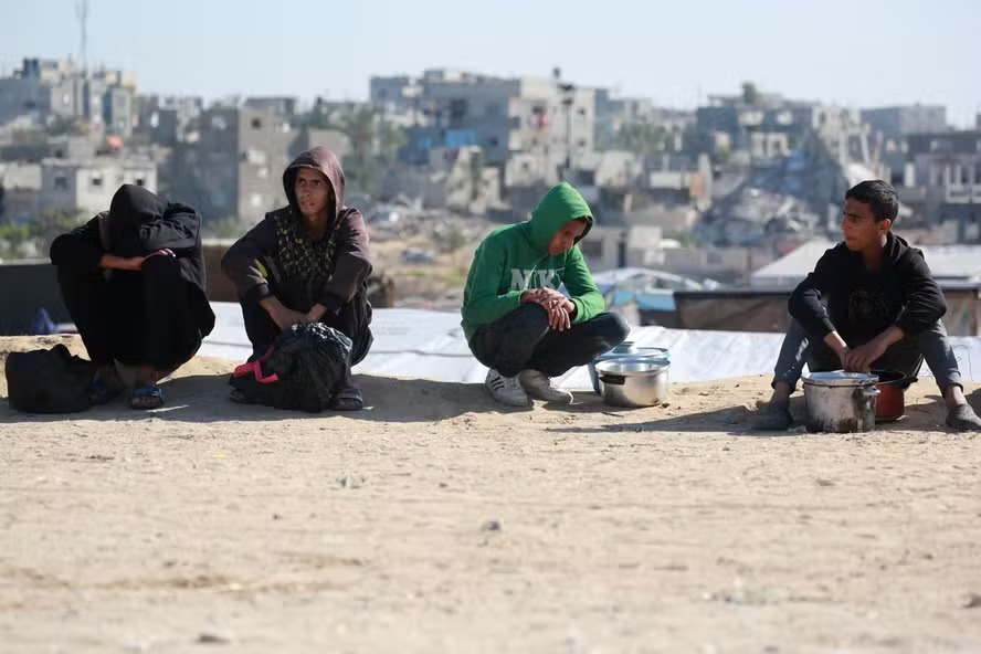 Palestinos esperam por porção de comida em um centro de distribuição ao sul de Khan Yunis 