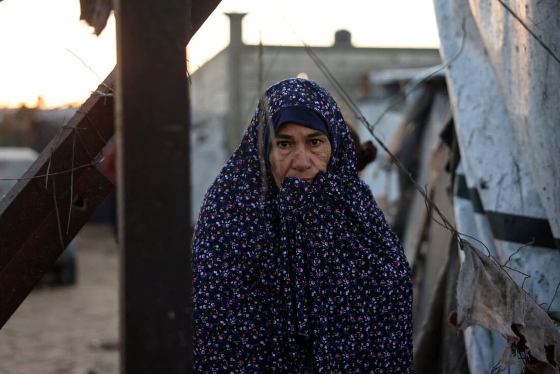 Uma mulher palestina deslocada fica em frente a uma tenda danificada após um ataque israelense noturno a um campo de deslocados improvisado em Mawasi Khan Yunis, no sul da Faixa de Gaza.