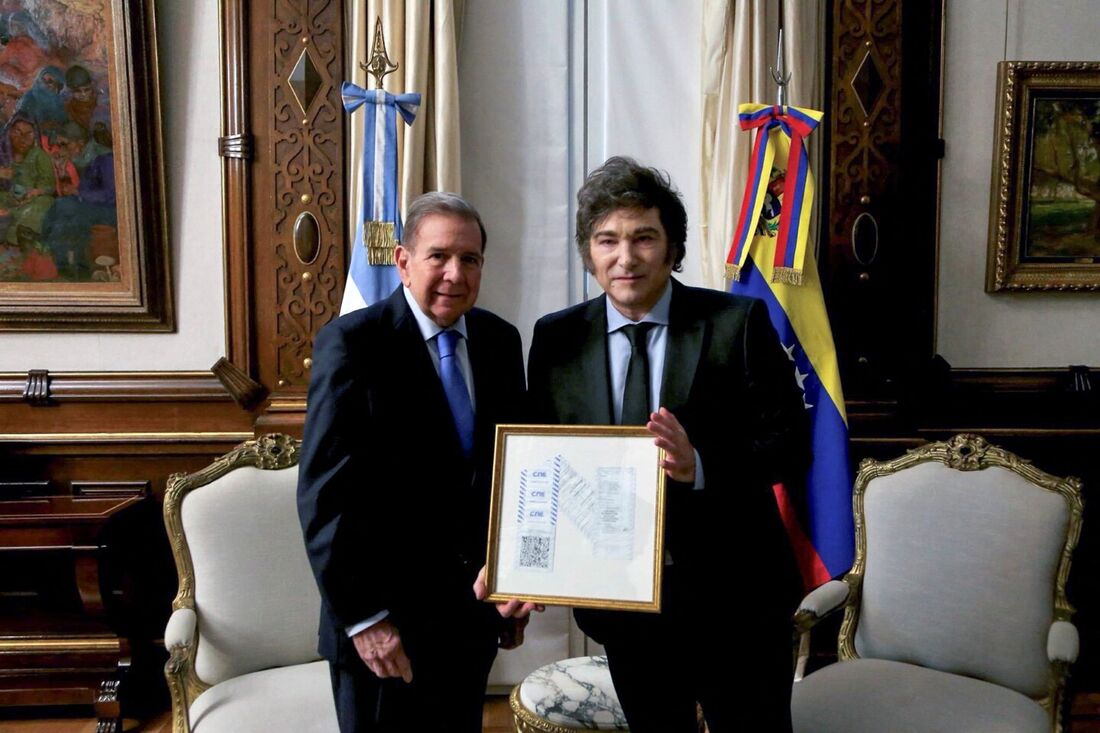 Presidente argentino Javier Milei (D) segurando um registro eleitoral das eleições venezuelanas, um presente do líder da oposição Edmundo Gonzalez Urrutia (E), em Buenos Aires