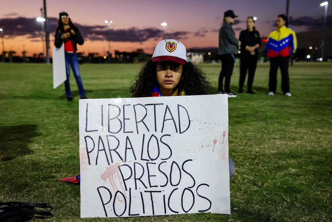 Uma mulher segura uma placa com os dizeres "liberdade para presos políticos" enquanto as pessoas participam de um protesto contra o governo do presidente venezuelano Nicolás Maduro