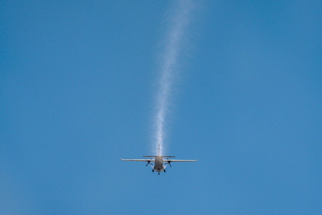 Pequeno avião pulveriza gelo seco sobre uma espessa camada de poluição atmosférica, em Bangcoc