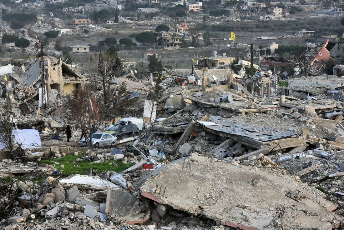 Pessoas em meio aos escombros de prédios destruídos durante a ofensiva terrestre e aérea de Israel após retornarem à vila de Aita al Shaab, no sul do Líbano