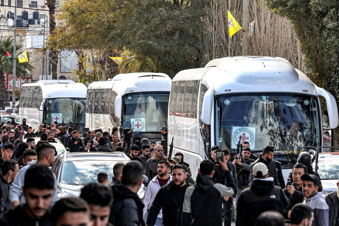 Ônibus do Comitê Internacional da Cruz Vermelha (CICV) transportando prisioneiros palestinos libertados por Israel circulam na cidade de Beitunia, perto de Ramallah, na Cisjordânia ocupada, neste sábado (25)