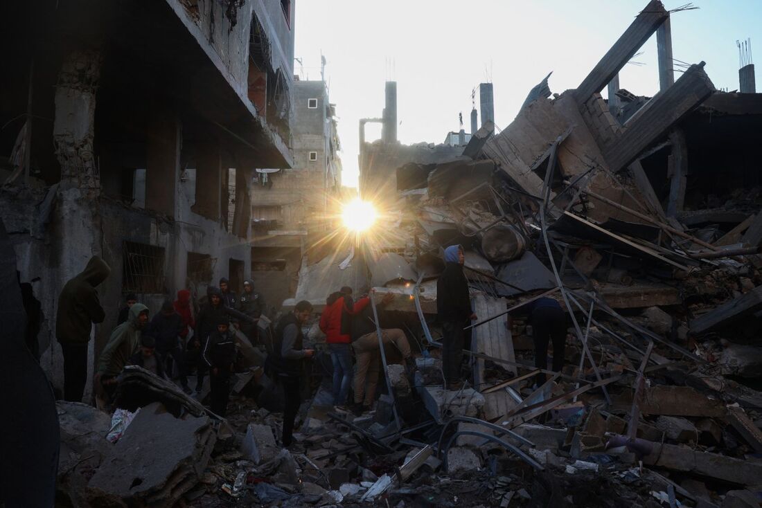 Pessoas revirando as ruínas de um edifício destruído por um bombardeio israelense, no campo Bureji para refugiados palestinos na Faixa de Gaza