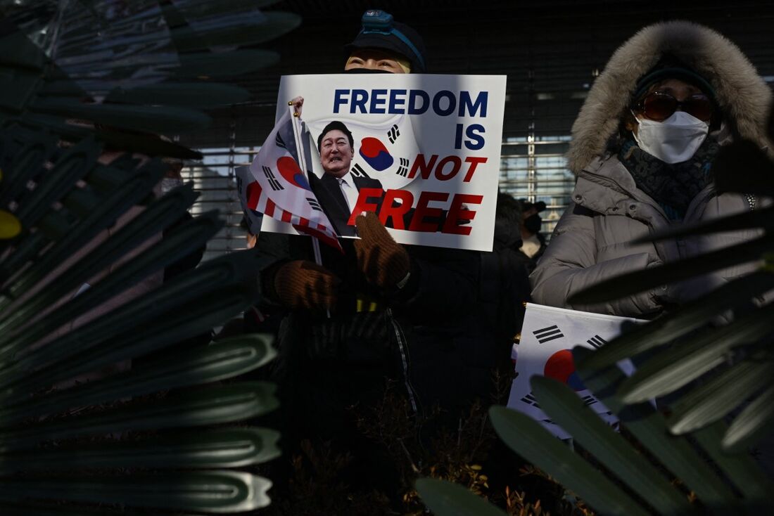 Um defensor do presidente da Coreia do Sul acusado de impeachment, Yoon Suk Yeol, segura um pôster com uma foto de Yoon com o texto que diz "A liberdade não é de graça", durante um comício perto de sua residência em Seul, em 8 de janeiro de 2025