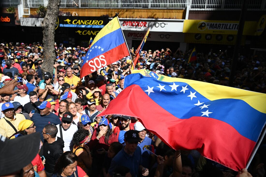 Manifestantes agitam bandeiras venezuelanas durante um protesto convocado pela oposição na véspera da posse presidencial em Caracas, em 9 de janeiro de 2025