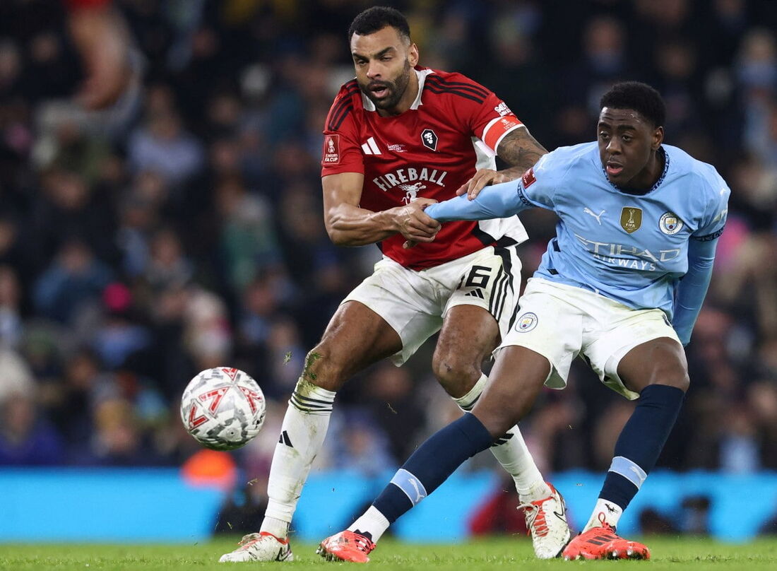 O zagueiro jamaicano #16 Curtis Tilt (E) do Salford City compete com o atacante inglês #67 Divin Mubama do Manchester City durante a partida de futebol da terceira rodada da FA Cup entre Manchester City e Salford City