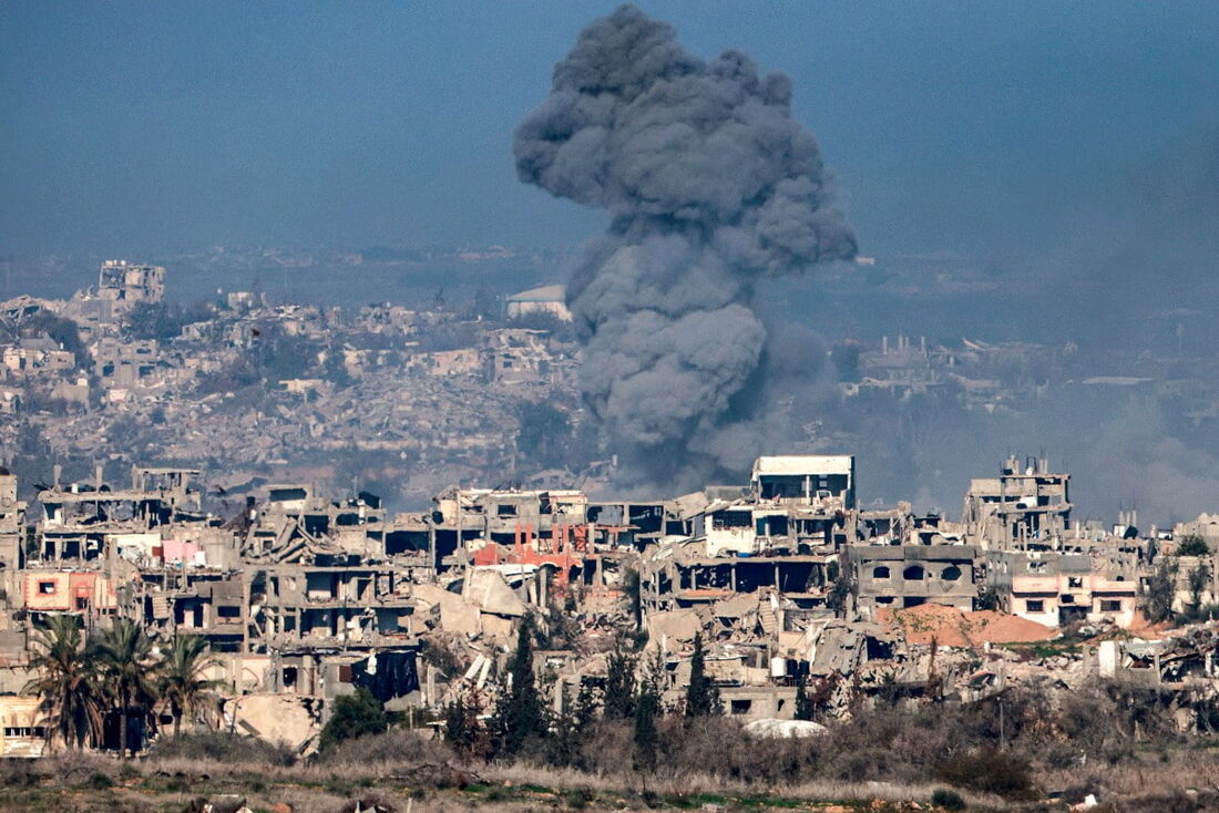 Coluna de fumaça subindo de explosões acima de edifícios destruídos no norte da Faixa de Gaza