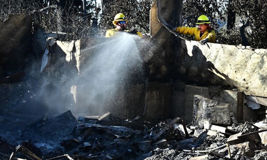 Bombeiros pulverizam os escombros de casas devastadas pelo fogo em Altadena, Califórnia