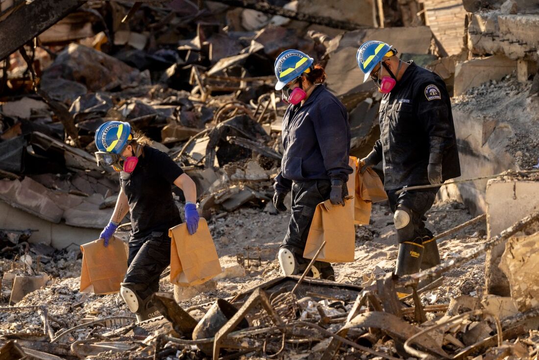 Médicos legistas do escritório do legista do condado de Los Angeles partem depois de revistarem uma casa destruída pelo incêndio em Palisades, onde os restos mortais das vítimas seriam enterrados em Malibu, Califórnia, em 15 de janeiro de 2025