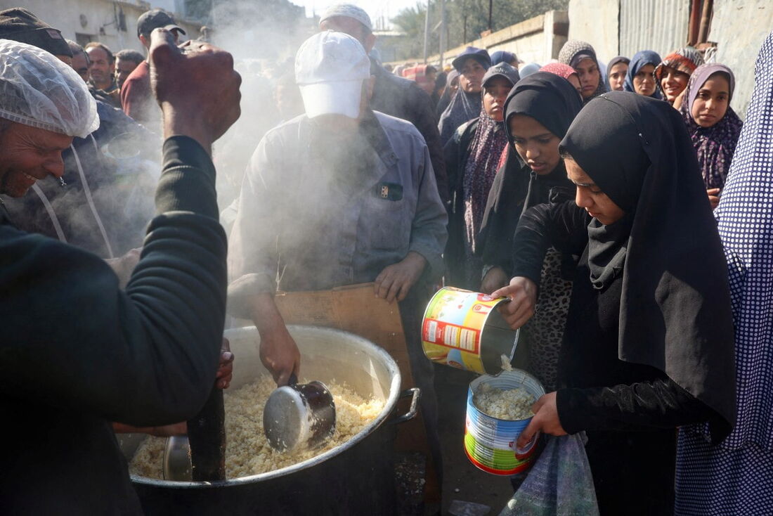 Palestinos se reúnem para receber alimentos de ajuda que estão sendo distribuídos em Deir al-Balah, no centro da Faixa de Gaza