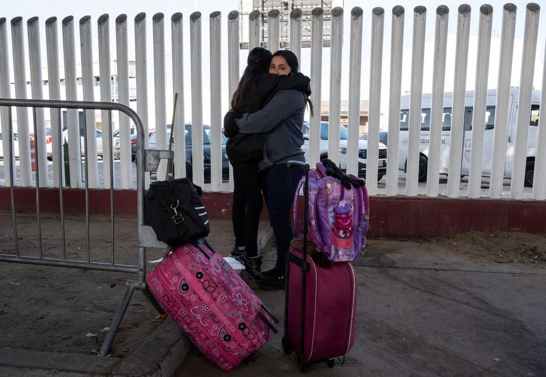 A solicitante de asilo de El Salvador Silvia Martinez segura sua filha Maria, enquanto elas aguardam suas consultas do CBP One com as autoridades dos EUA antes de cruzar o porto de El Chaparral em Tijuana