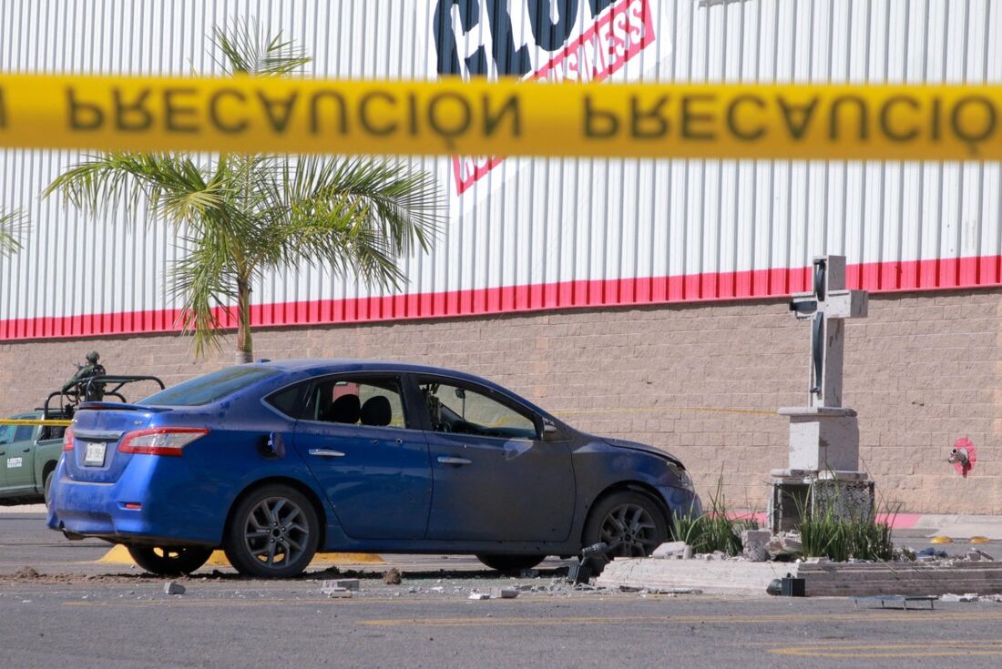 Um carro baleado deixado ao lado do memorial danificado dedicado a Edgar Guzmán López, filho de 