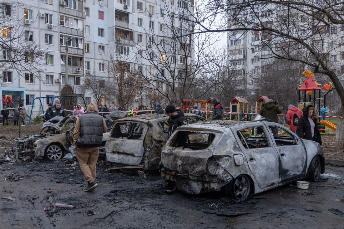 Moradores locais inspecionam carros queimados estacionados no pátio de um prédio residencial após um ataque com mísseis em Odessa em 28 de janeiro de 2025