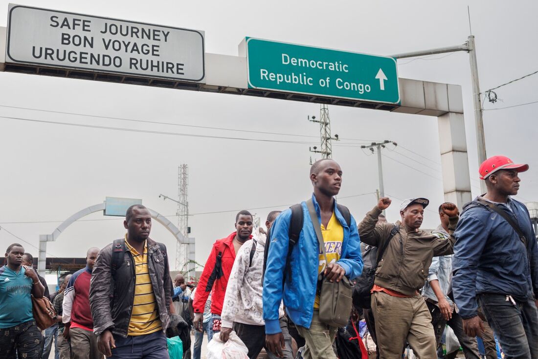 Civis que ficaram presos pelos conflitos em andamento no leste da República Democrática do Congo reagem após cruzar para Ruanda em um ponto de fronteira em Gisenyi 