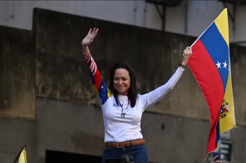 Líder da oposição venezuelana, Maria Corina Machado, agita bandeira nacional durante protesto convocado pela oposição na véspera da posse presidencial de Maduro, em Caracas