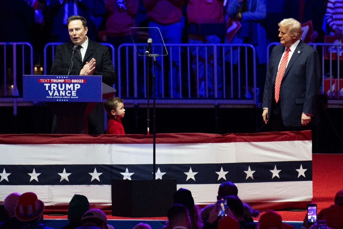  Donald Trump observa enquanto Elon Musk fala no comício da vitória no Capital One Arena