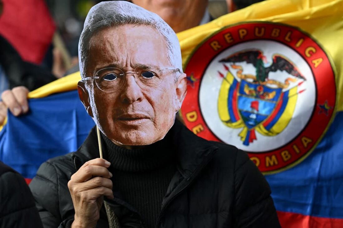 Um apoiador do ex-presidente colombiano Álvaro Uribe usa uma máscara com sua imagem enquanto protesta 