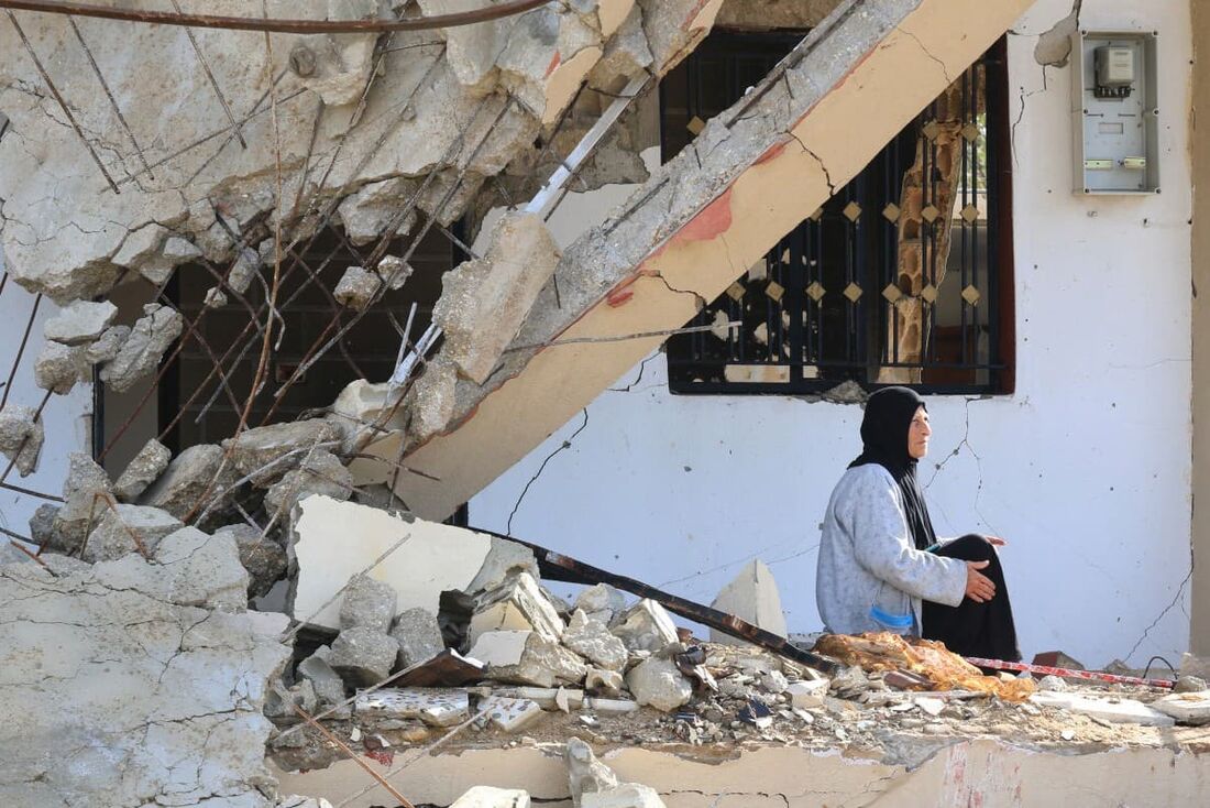 Uma mulher libanesa sentada em frente a um prédio destruído no recente bombardeio israelense