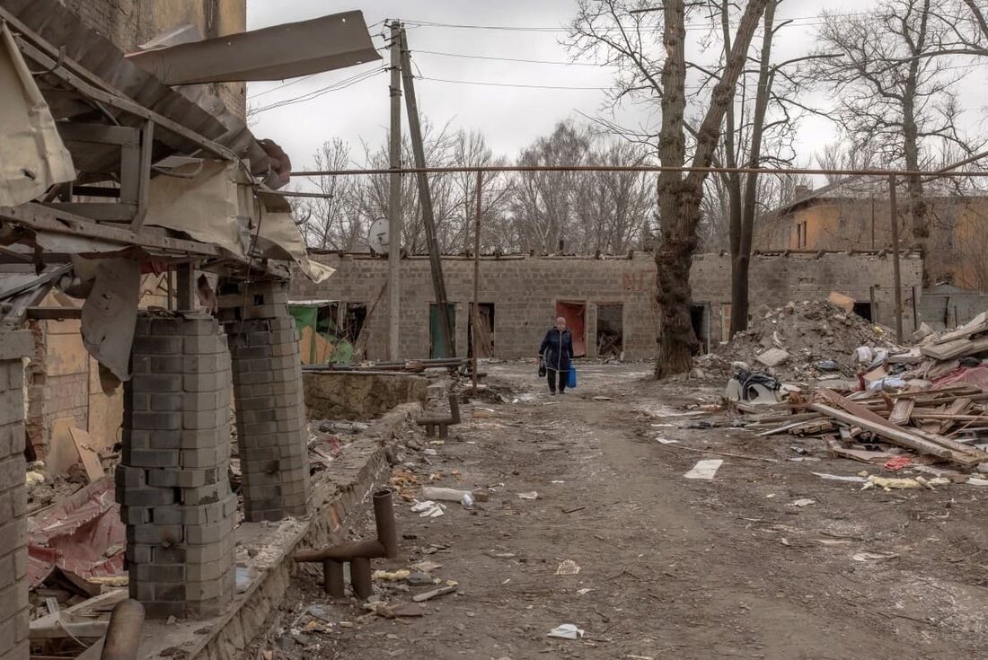 Uma mulher passa por destroços e prédios danificados após bombardeio em Kostyantynivka, na região oriental de Donetsk