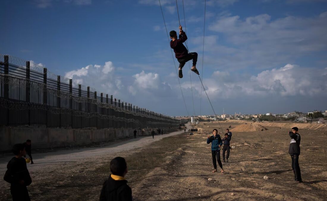 Palestinos brincam perto da fronteira entre o Egito e a Faixa de Gaza, ao longo do corredor Filadélfia