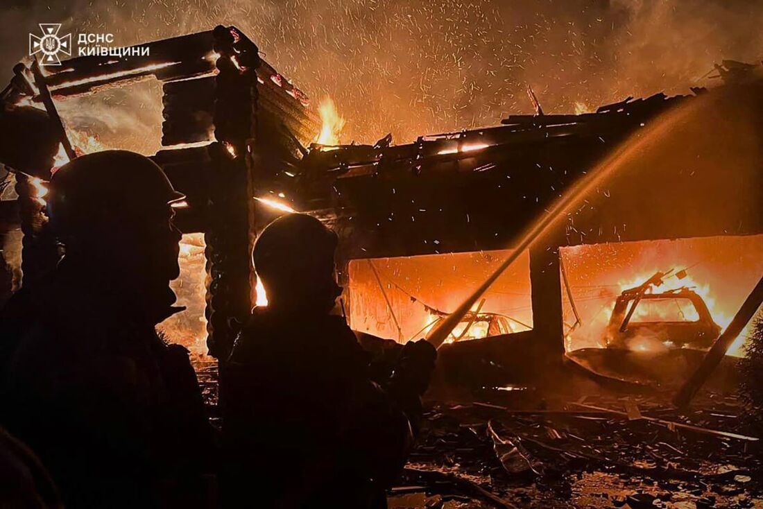 Equipes de resgate ucranianas apagando um incêndio em um prédio após um ataque de drones na região de Kiev