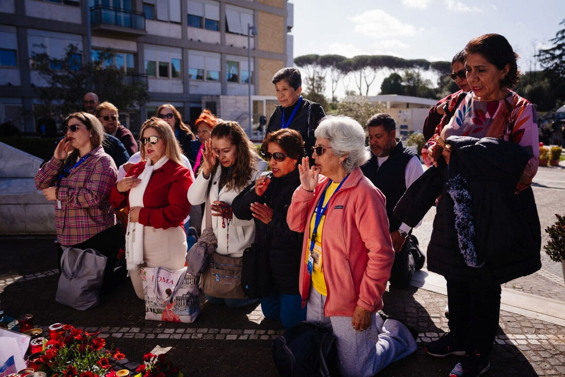 Pessoas rezam em frente à estátua de João Paulo II, do lado de fora do hospital Gemelli, onde o Papa Francisco está hospitalizado com pneumonia, em Roma