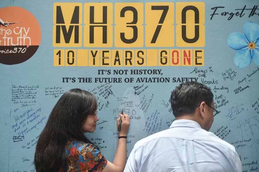 Mulher escreve mensagem em painel durante evento de parentes de passageiros do voo MH370