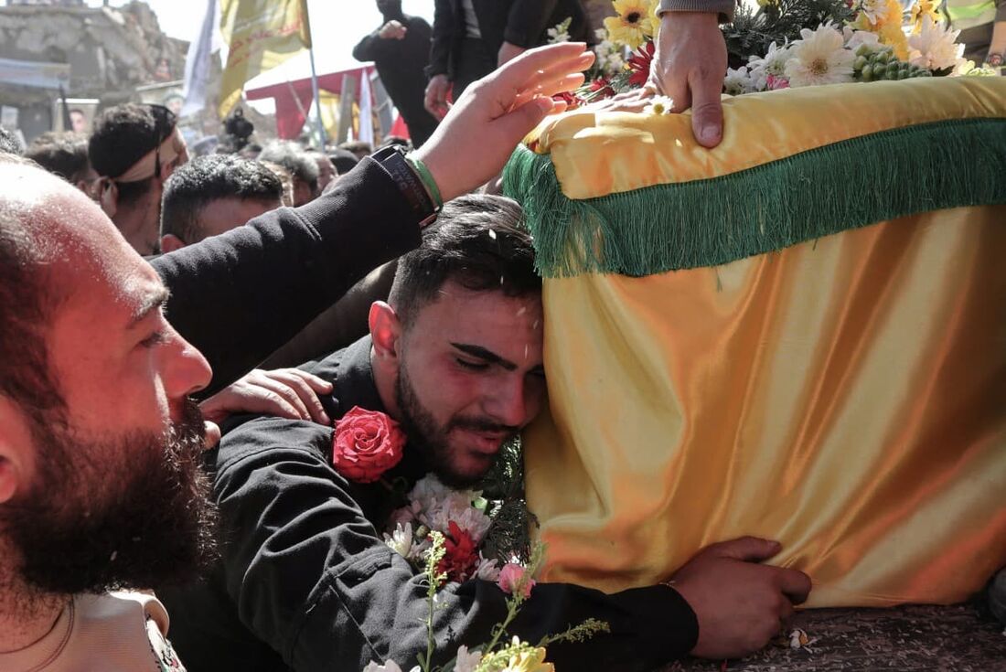 Um enlutado reage perto do caixão coberto com a bandeira de um combatente do Hezbollah, durante o cortejo fúnebre de militantes e civis mortos na recente guerra com Israel