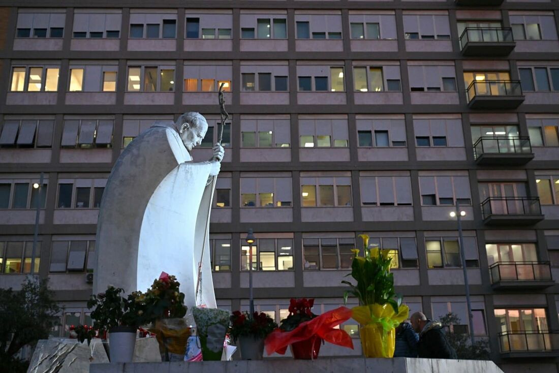 Flores são depositadas na estátua de João Paulo II do lado de fora do Hospital onde o Papa Francisco está hospitalizado