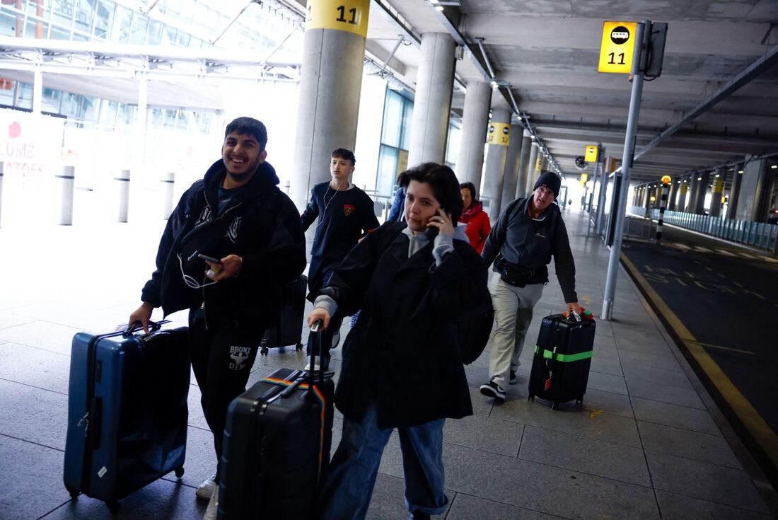 Passageiros com suas malas deixam o aeroporto de Heathrow após seu fechamento após um incêndio em uma subestação que fornecia energia para o aeroporto, em Hayes, oeste de Londres
